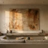 A wabi sabi plaster wall artwork with iron oxide earthy washes in rust and umber over rough joint compound texture, on a raw plaster wall above a stone shelf