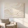 A flawless textured painting on canvas with layered palette-knife impasto waves in soft cream, hanging above a reading chair