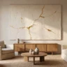 A plaster artwork with cracked texture filled with fine gold leaf seams, in ivory and gold, hanging in a softly lit living room