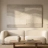 A soft modern neutral wall artwork in greige and warm white with gentle layered texture, hanging above a cream boucle sofa