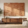 A textured acrylic canvas wall art with rich layered texture in terracotta and sand acrylic tones, hanging above a walnut credenza