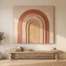 A designer DIY plaster rainbow artwork of layered arches in terracotta, blush and sand tones, hanging above a low wooden bench