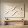 A DIY plaster canvas art piece that looks expensive, with crisp sculpted texture in warm white, hanging above a minimalist console