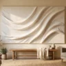 A textured canvas art piece that looks expensive, with soft sculpted waves in warm white, hanging above a simple wooden bench